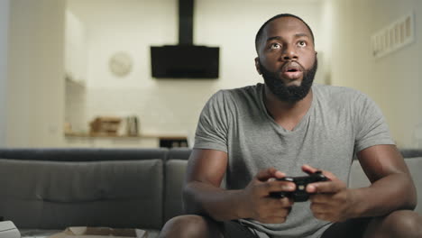 Smiling-black-man-playing-video-game-at-home-kitchen.