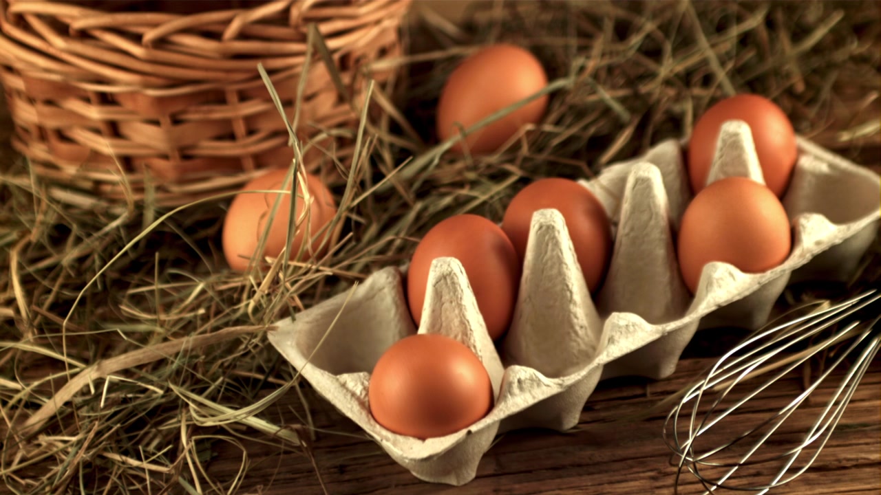 Sakte film av et brunt egg som faller ned i en kartong