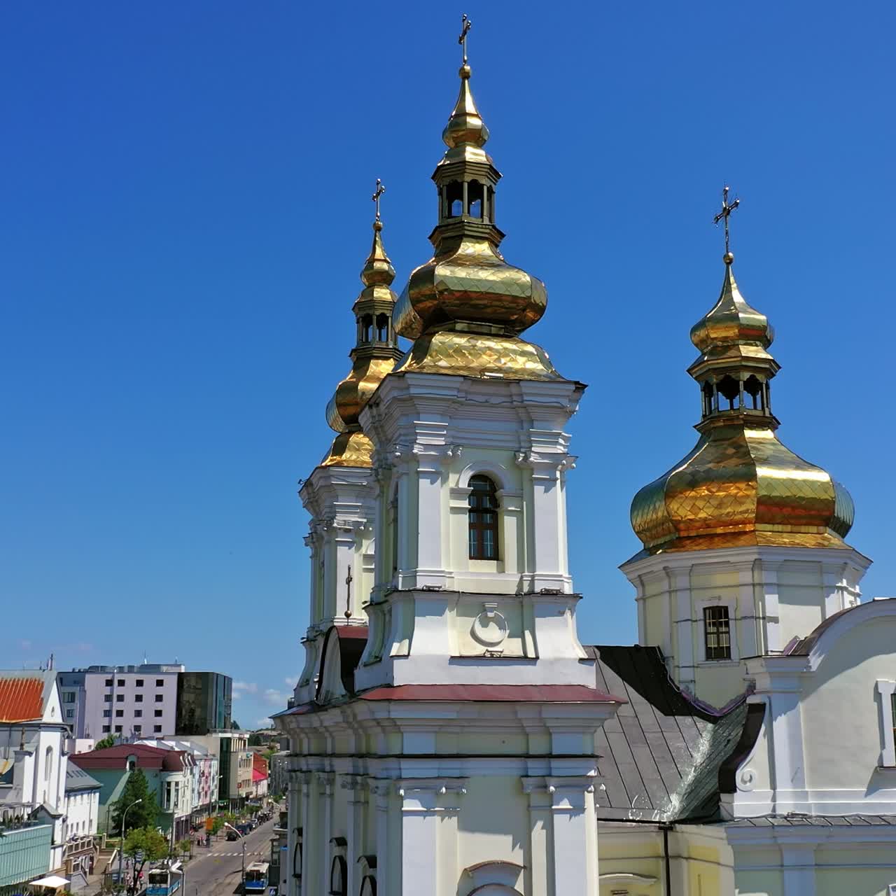 Beautiful Christian cathedral with golden cupolas shining in the bright sun. Lively city in summer. Clear blue skies above the church