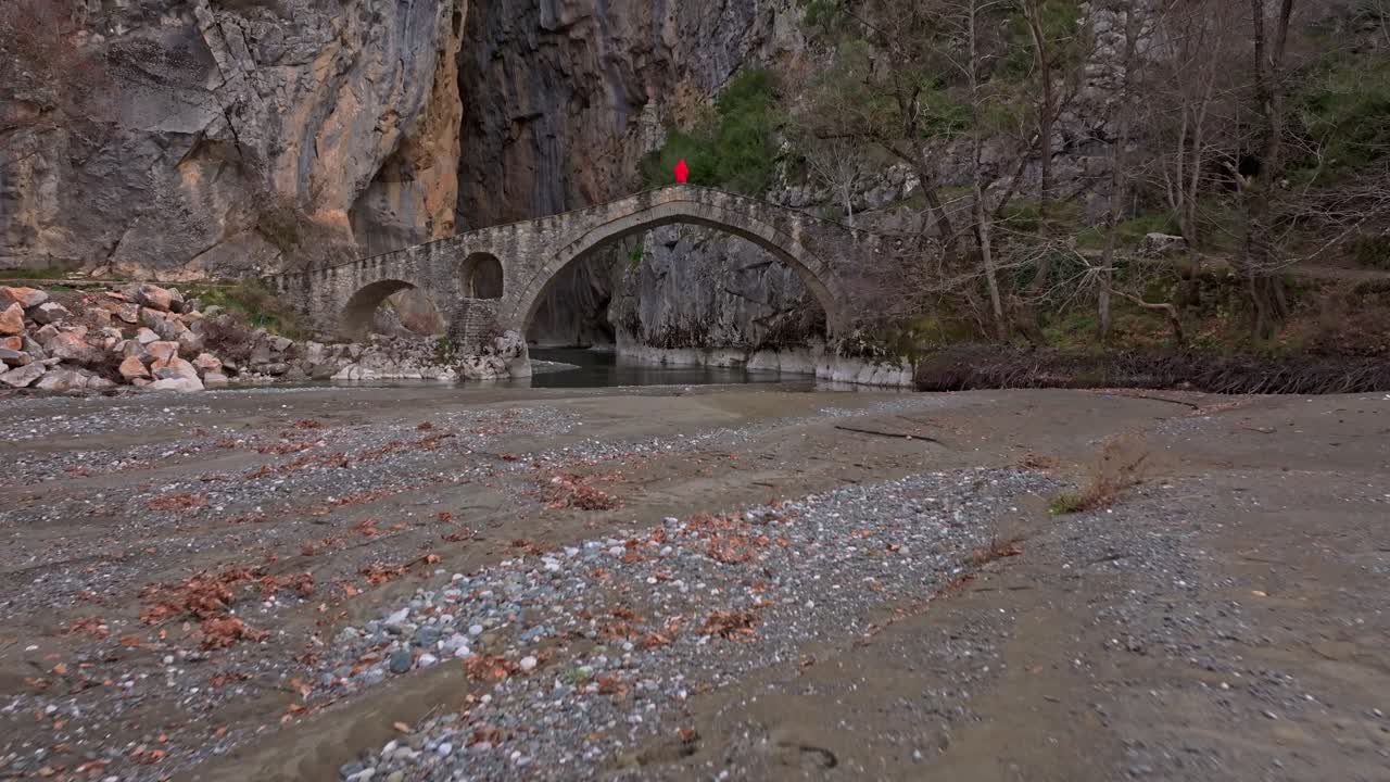 Yunanistan, Portitsa Kanyonu'nda taş köprüdeki bir adamın drone görüntüsü.