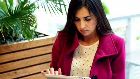 Businesswoman-using-digital-tablet-while-having-cup-of-coffee