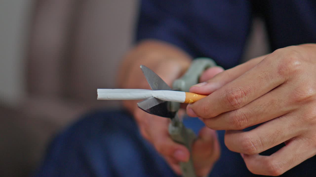 Detalhe das mãos usando tesoura para cortar um cigarro ao meio