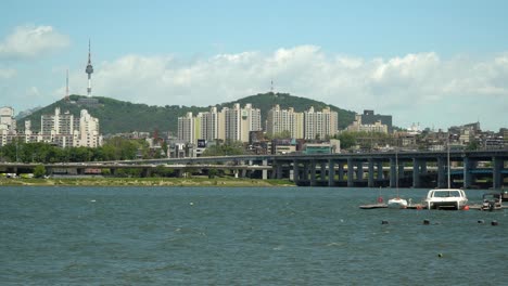 han river, namsan tower and double-deck banpo bridge on background, catamaran, and boat floating on water