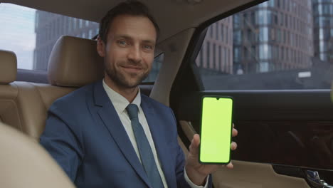 businessman showing green-screened smartphone on camera