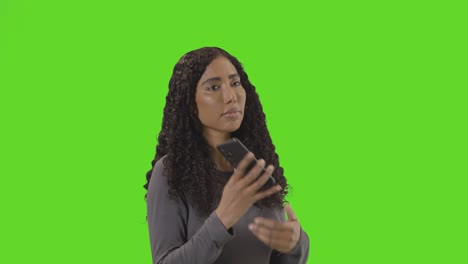 sad woman talking on mobile phone getting bad news against green screen