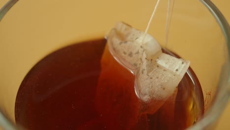 close-up of a tea bag steeping in a glass of water