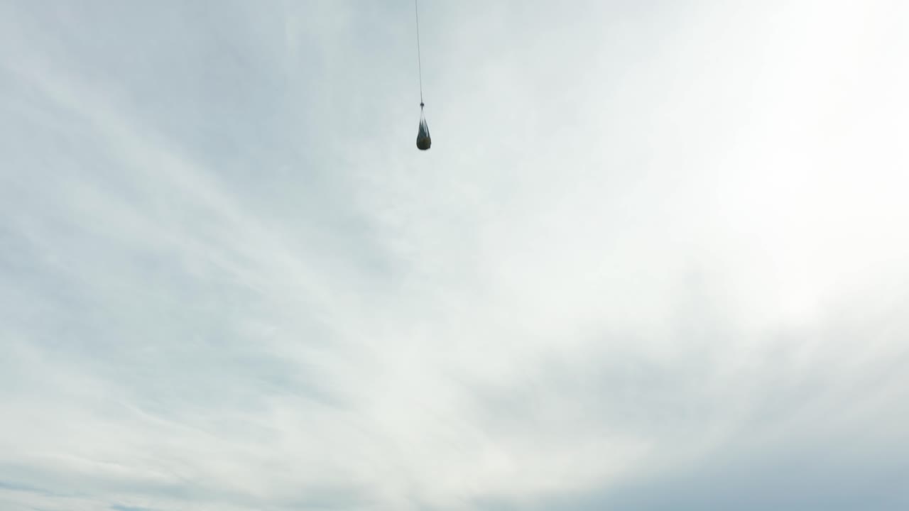 흐린 날 비행하는 케이블에 매달린 그물에 물품을 운반하는 헬리콥터