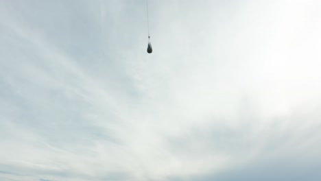 helicóptero que transportaba suministros en la red colgando del cable que volaba en un día nublado
