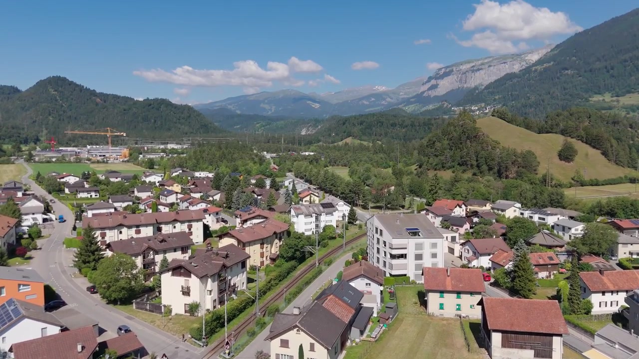Luftaufnahme des Dorfes Bonaduz in Graubünden, Schweiz, mit grünen Feldern und Bergen im Hintergrund