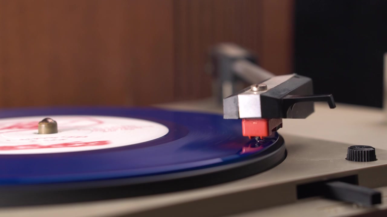 Disco in vinile blu che gira sotto la puntina del grammofono, fumo di sigaretta che si muove sopra.