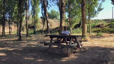 man sitting at a wooden table in the forest-1