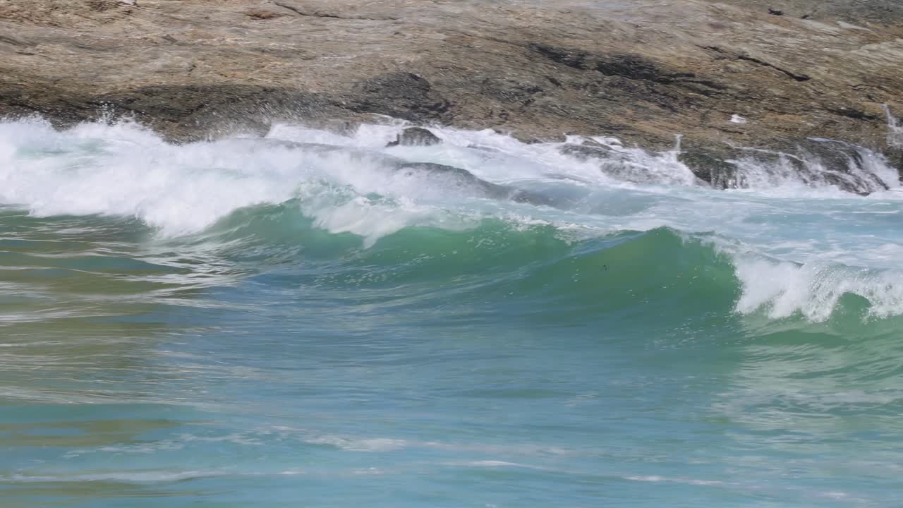 Close-up view of ocean waves rolling and crashing over a rocky shoreline, showcasing dynamic water movement.