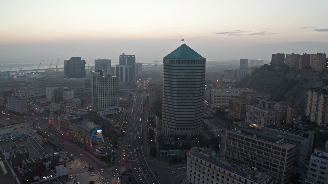 Aerial view of a bustling city at dusk with a prominent skyscraper and harbor