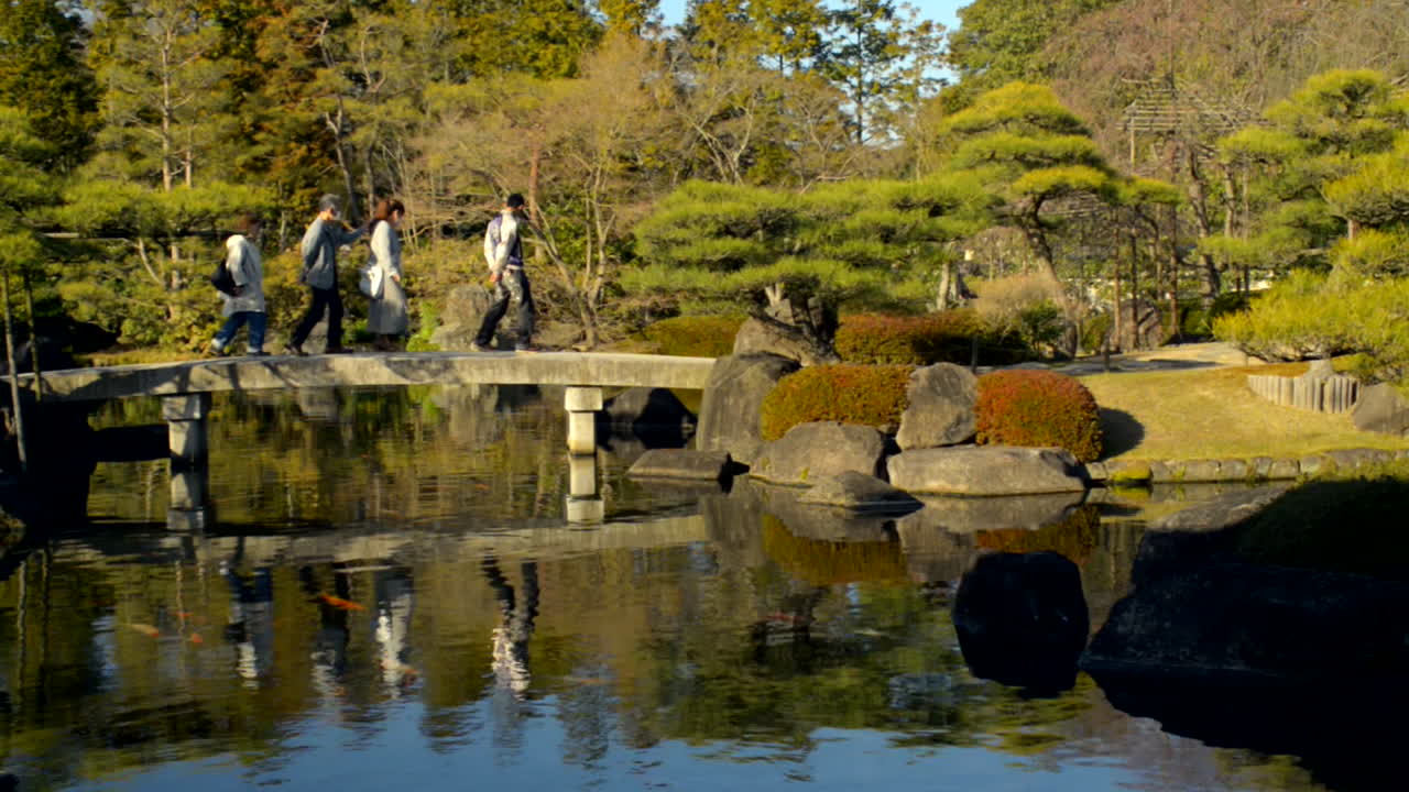 Visitors walking over a stone bridge. Located in the Japanese Garden next to Himeji Castle