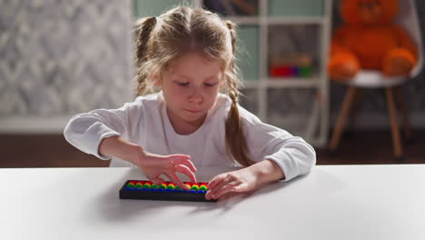 little student learns to solve tasks with abacus at desk