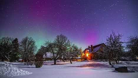 aurora borealis and milky way in the sky over snowy landscape with trees and wooden house with warm lights