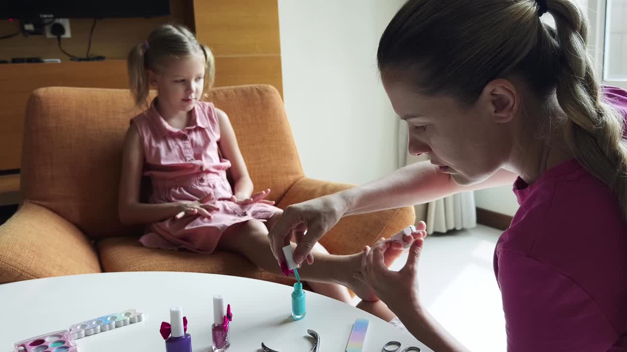mãe e filha em casa a fazer as unhas.