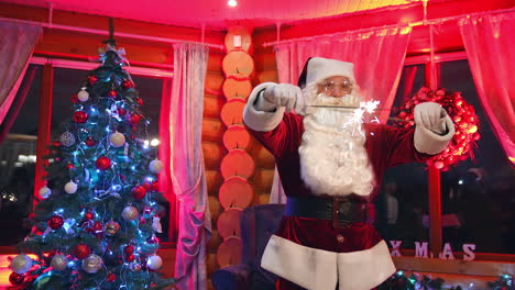 funny santa with christmas lights dancing in the house. real santa claus with white beard in glasses standing near beautiful christmas tree. santa looks at camera.