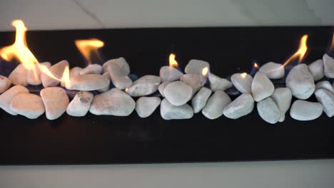 Close-up-slow-motion-tracking-shot-from-above-of-indoor-gas-fire-place-with-white-pebbles