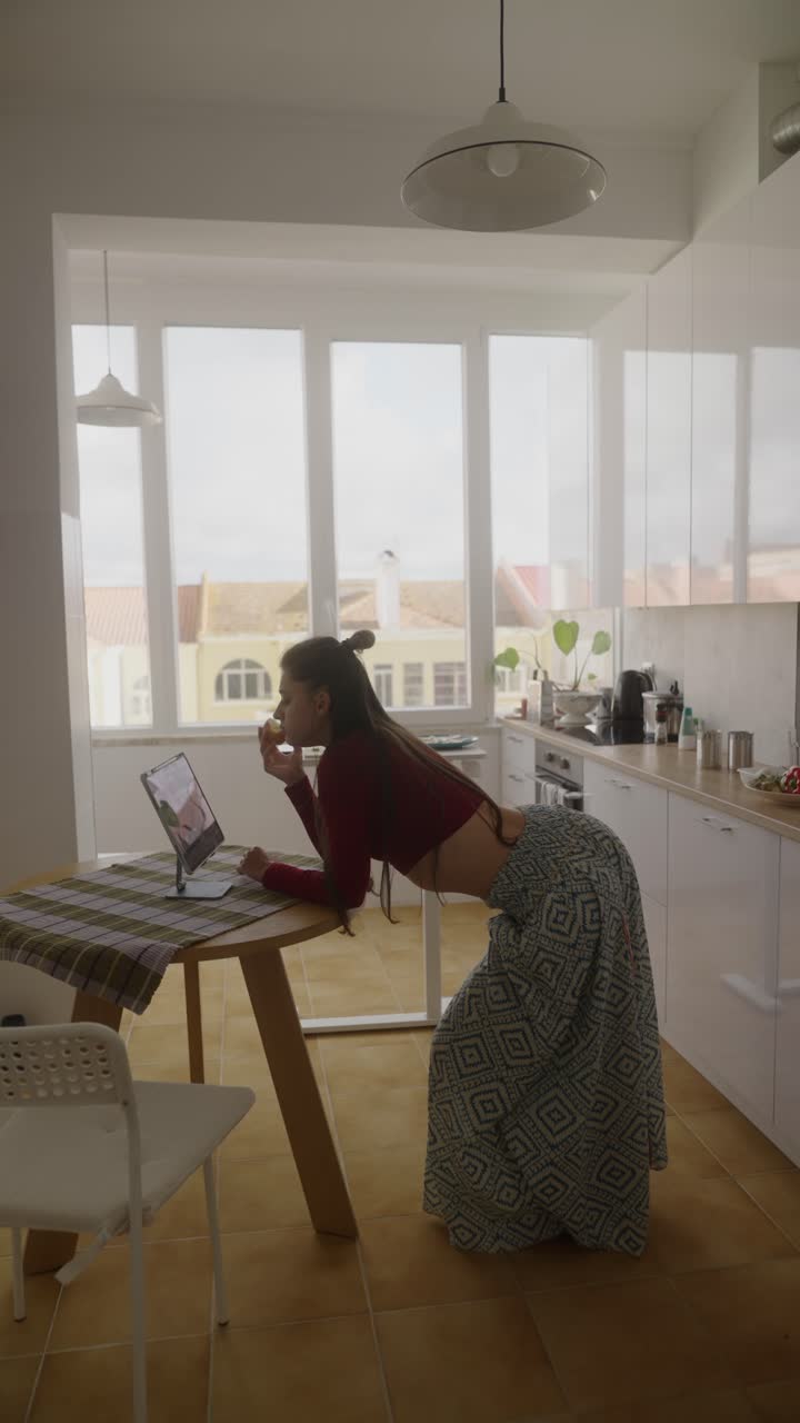 Donna che mangia in videochiamata in cucina