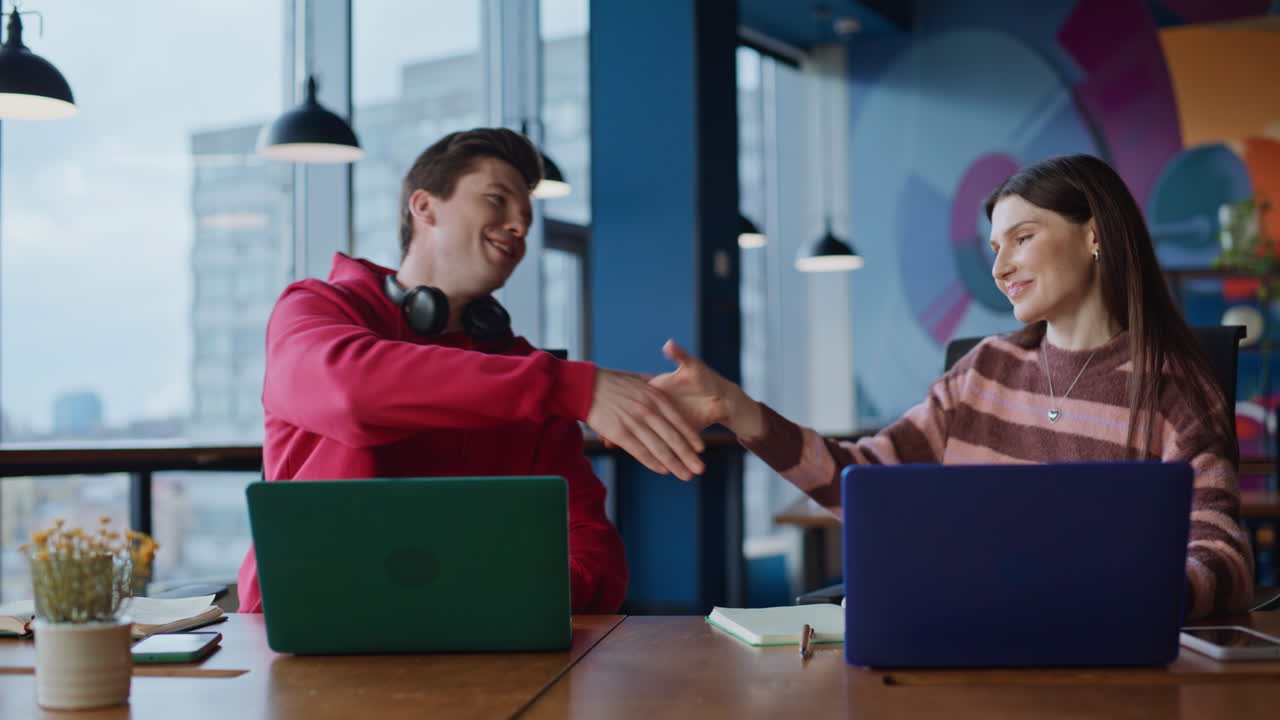 Two people working together at an office, shaking hands