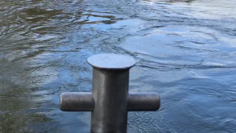 close up of the waikato river flowing gently passed the boat anchor capstan on a bright day in hamilton new zealand