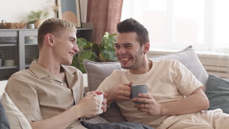 two young men sitting on sofa and communicating