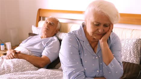 Worried-senior-woman-sitting-on-bed