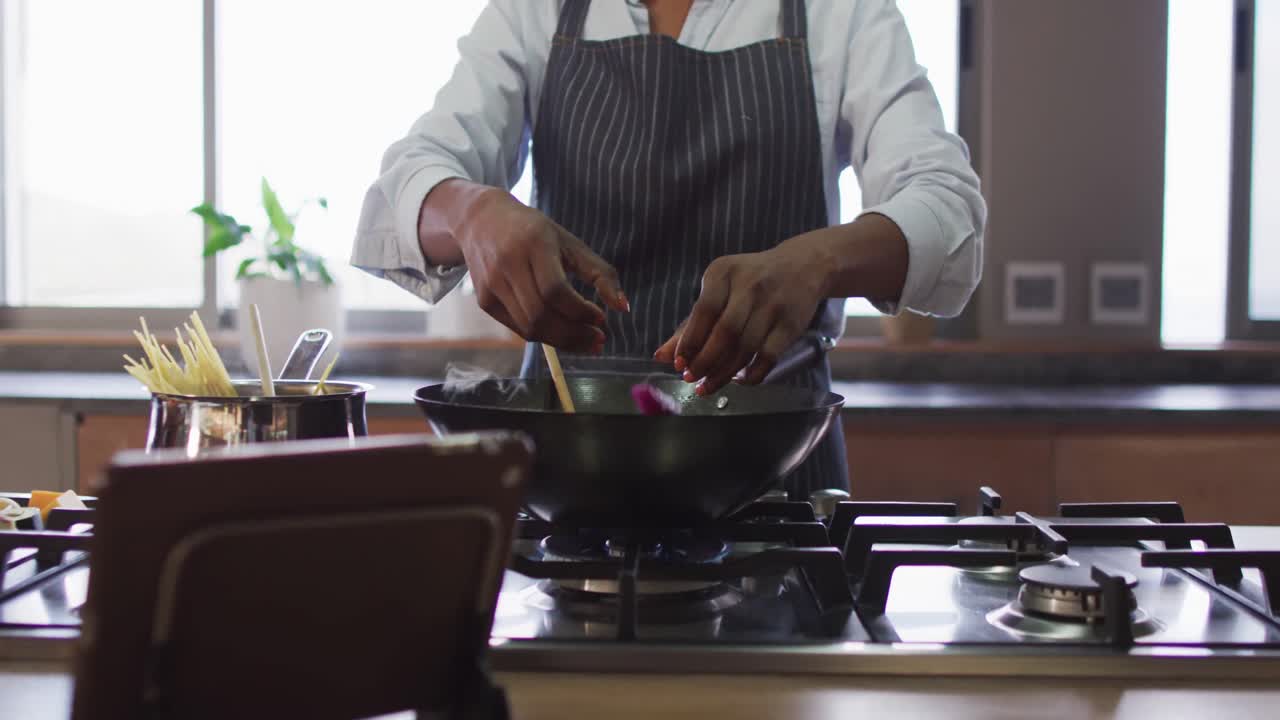 Video bagian tengah tubuh wanita birasial sedang menyiapkan makanan.
