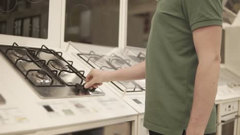 man looking at gas stove in a kitchen appliance store