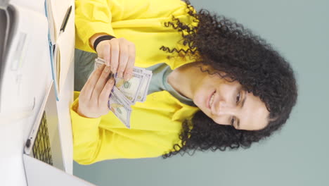 Vertical-video-of-Young-woman-looking-at-laptop-counting-money.