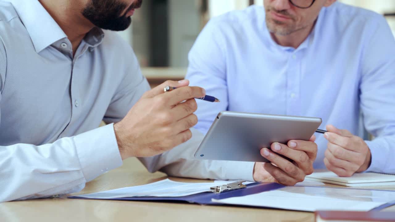 dos hombres de negocios diversos analizando datos financieros usando una tableta digital.