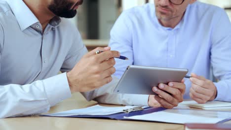 dos hombres de negocios diversos analizando datos financieros usando una tableta digital.