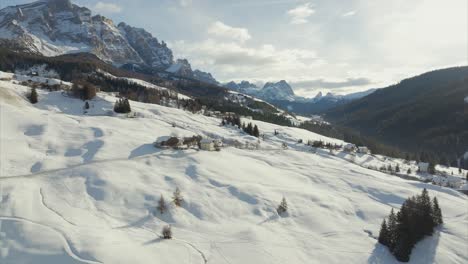 Stunning-orbiting-aerial-view-of-idyllic-ski-resort-atop-snow-covered-slopes-of-Val-Badia,-Italy