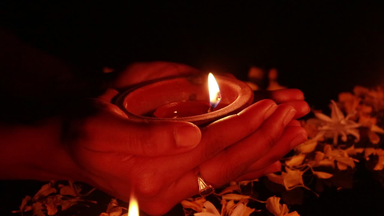 Hands slowly placing a mud lamp in the dark