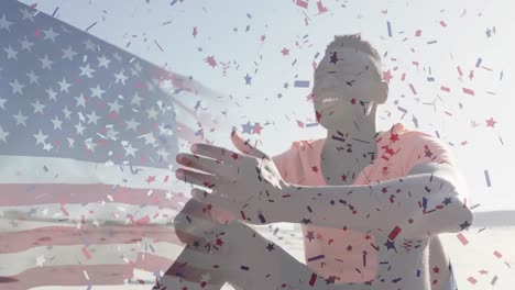 animation of flag of united states of america and confetti over african american man on beach