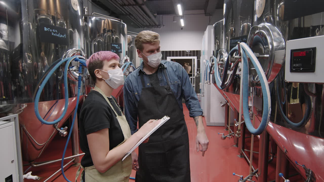 Brewery Workers Inspecting Beer Production Equipment