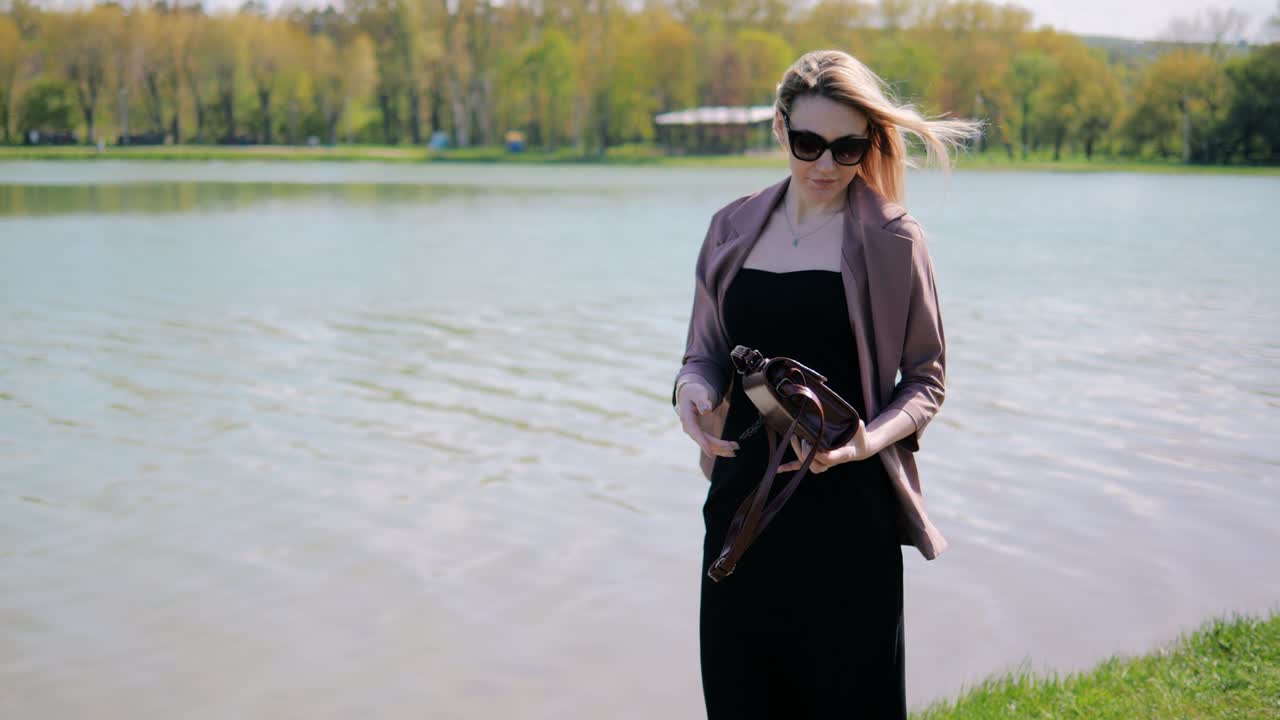 호수 의 공원에서 아름다운 젊은 여성이 더 아름답게 되기 위해 드백에 거울을 찾고 있습니다.