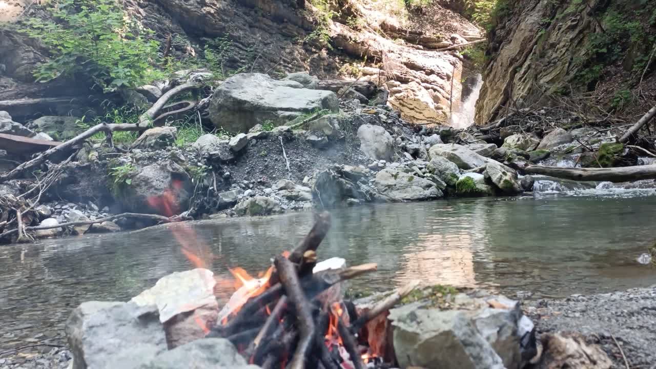 la hoguera arde en la naturaleza sin gente con cascada y río en el fondo