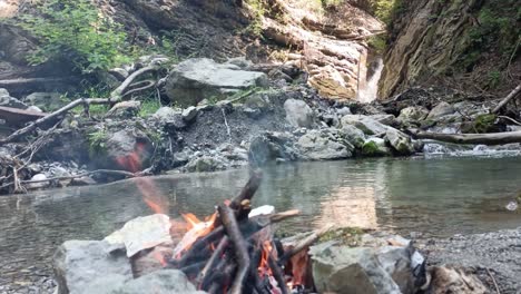 bonfire is burning in nature with no people with waterfall and river in background