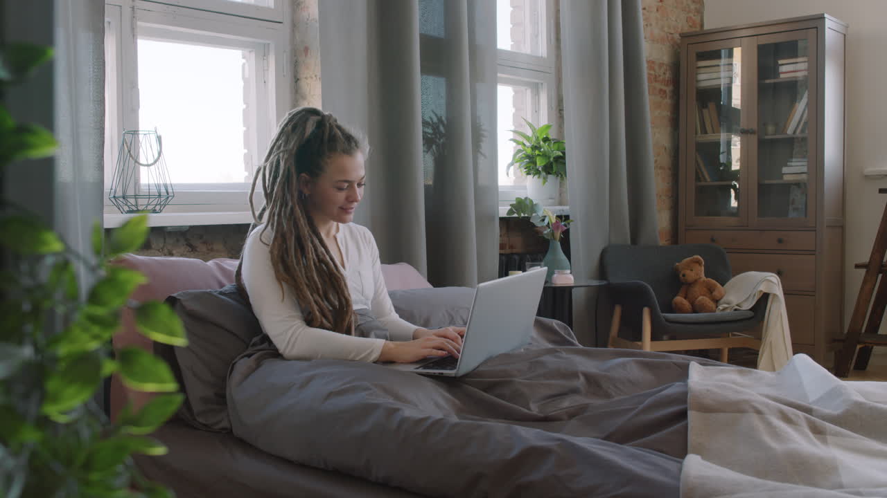 Female Freelancer Working In Bed