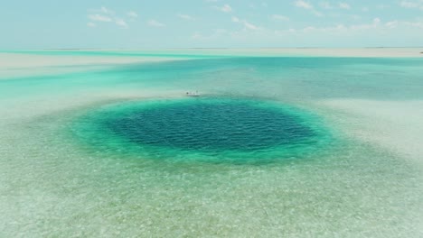 aerial view approaching bahamas blue hole with fishing boat at edge