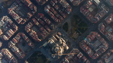 High-angle-view-of-construction-site-of-famous-unfinished-basilica-Sagrada-Familia-and-surrounding-blocks-of-buildings.-at-golden-hour.-Barcelona,-Spain