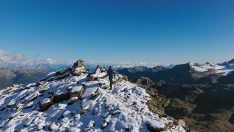 athletic hiker walking on snowy ridge mountaintop with panorama in background, cima fontana, valmalenco in italy