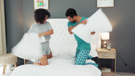 pareja feliz, amor y pelea de almohadas en la cama