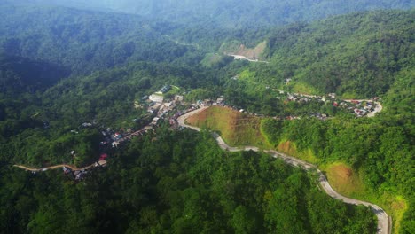 carretilla aérea por encima de la aldea tropical construida a lo largo de una sinuosa carretera de montaña