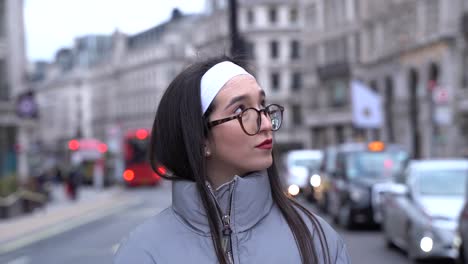 linda chica de pie en la calle de londres, esperando a alguien, mirando a su alrededor