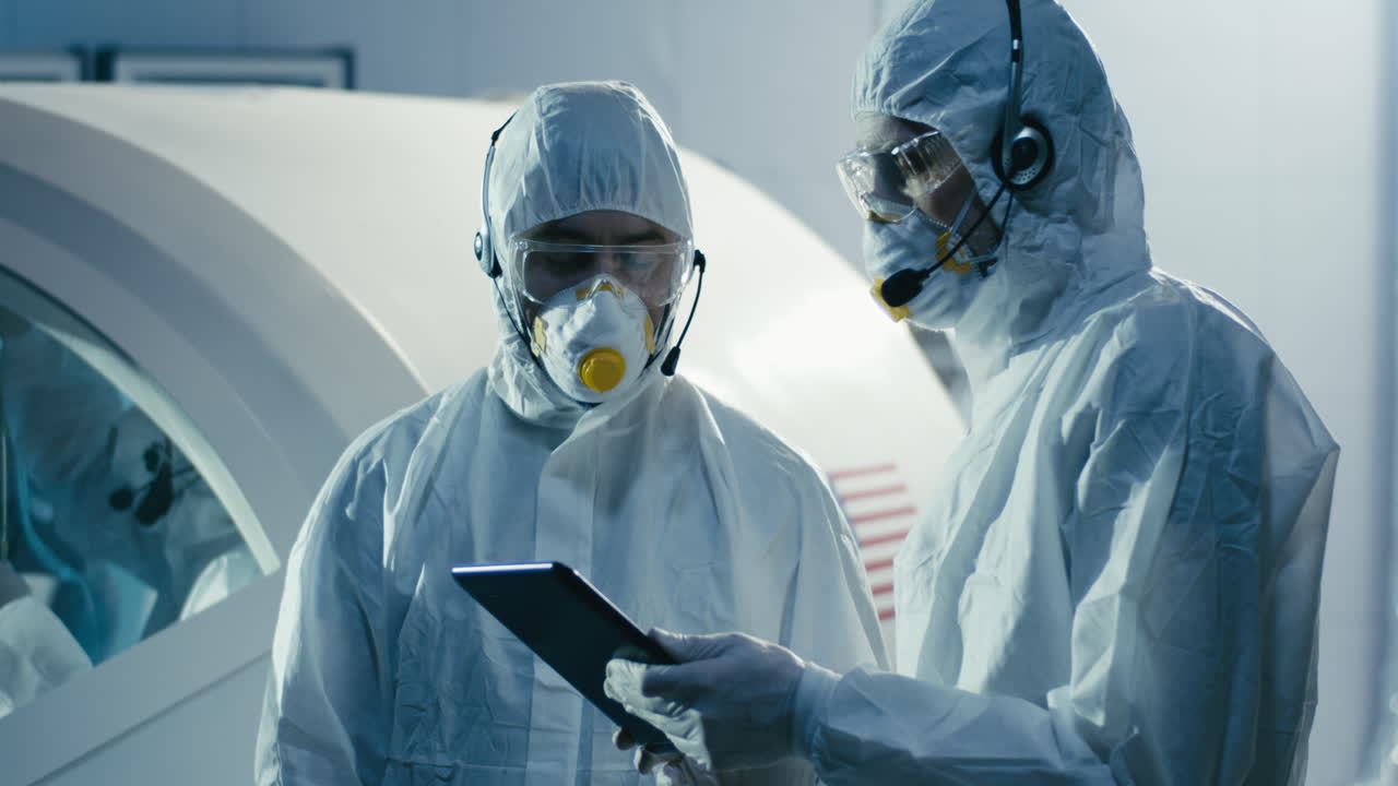 Scientists in Protective Gear Reviewing Data on a Tablet