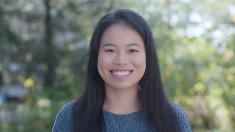 Close-up-of-young-Asian-American-woman-smiling-at-camera,-slow-motion