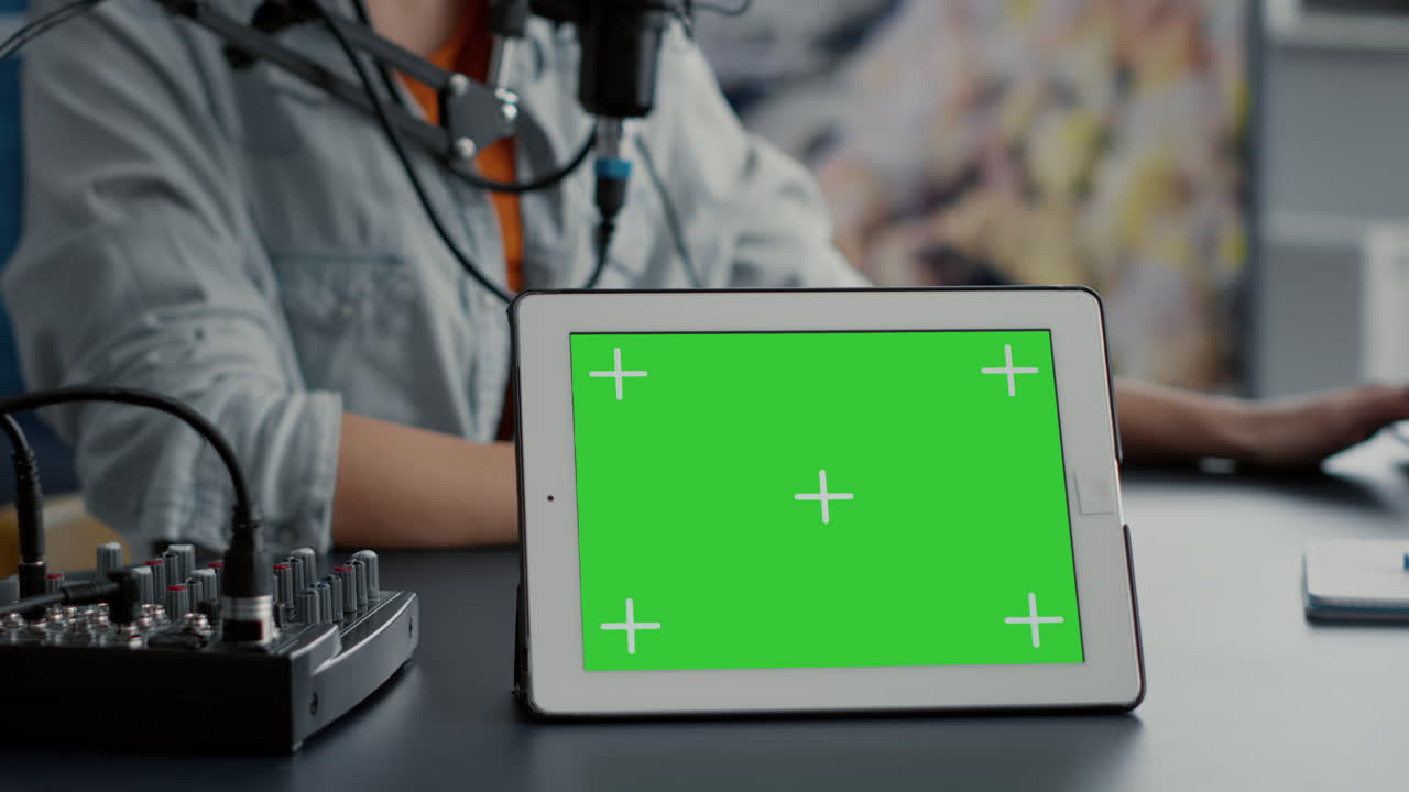 Tablet with chroma key with isolated background and mockup template standing on podcast studio desk